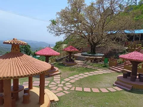 A covered sitting area having small huts in a garden on hills Фото