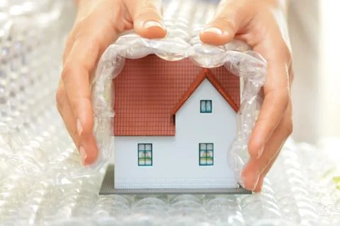 Covering a model house with bubble wrap- house protection or insurance concept Stock Photos