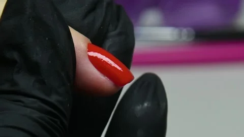 Covering the nail with red macro varnish. a manicurist paints her nails red  Stock Footage 221361678