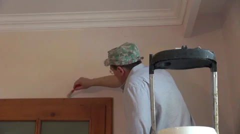 Covering walls with a new paint, worker on a ladder, paint brush, new home Stock Footage 38348574