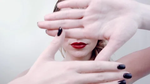 Covers face hands, shows and advertises red lipstick on her lips, smiles and ope Stock Footage 84142641