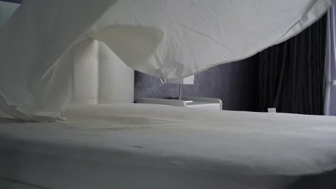 Covers the sheets on a white bed. White fabric is thrown up and lays do 库存影片 90132598