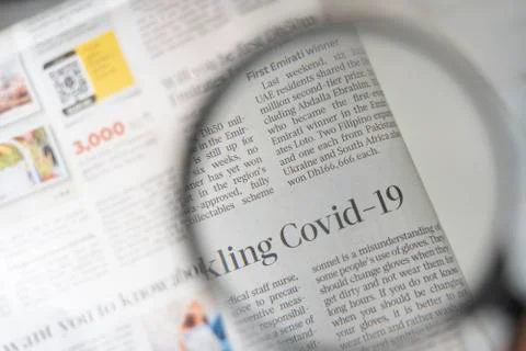 Covid 19 article through a magnifying glass Stock Photos