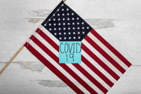 COVID 19 on blue note sitting on American flag flat lay background Stock Photos
