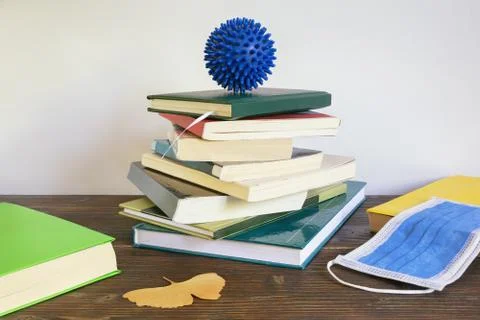 Covid-19 concept. Stack of books with face protective mask on table Stock Photos