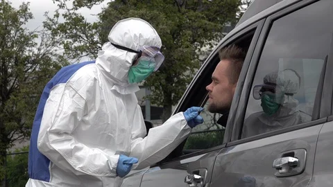 Covid-19 drive through test clinic, nurse in protective hazmat suit Stock Footage