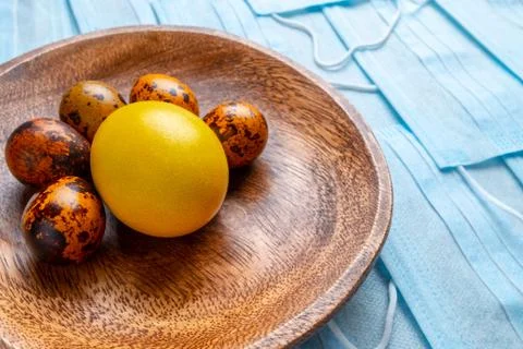 COVID-19 Flat lay. Colored Easter eggs on a background of blue medical masks Stock Photos