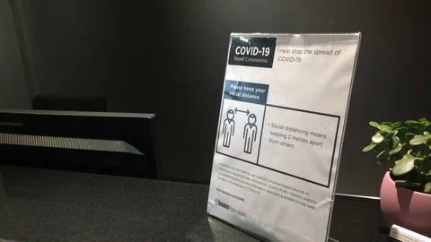 COVID-19 Instructions are displayed atop a reception desk in Toronto Stock Footage 127850867