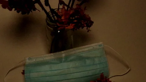 COVID-19 Mortality Face Mask with Dead Flowers in Yellow Orange Light Video stock 148226151