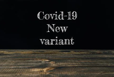 Covid-19 new variant text displayed on a wooden table with dark background for Stock Photos