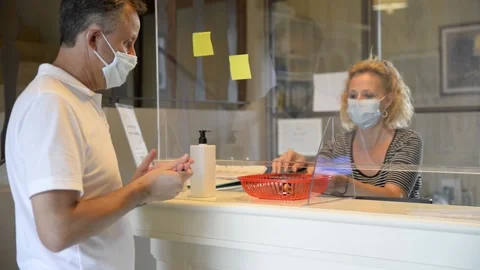Covid-19 pandemic forces people to be separated by a plexiglass screen in hotel Stock Footage