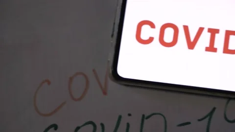 Covid-19 red writing on a screen of a mobile phone Stock Footage 130597257