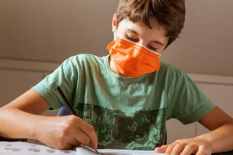 Covid 19 Schoolboy doing homework and wearing surgical mask Stock Photos