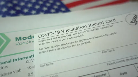 COVID 19 Vaccination Record card over Moderna Covid 19 Vaccine information pa Stock Footage