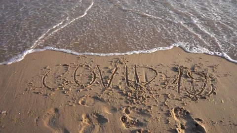 Covid-19 is written on the sandy beach and is washed away by the wave of the sea 스톡 동영상 135931005