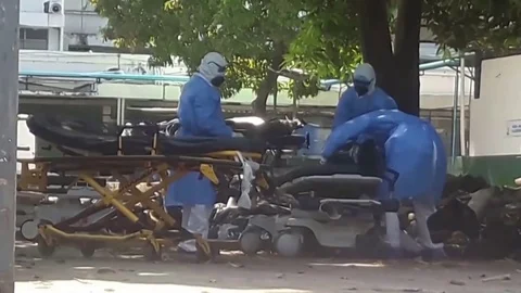 COVID-19.Men in protective suits take out corpses in black bags. Stock Footage 128770326