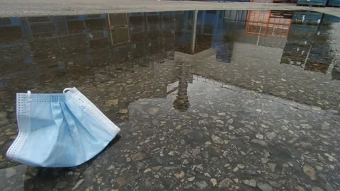 Covid face mask in a rain puddle Stock Footage 170775004