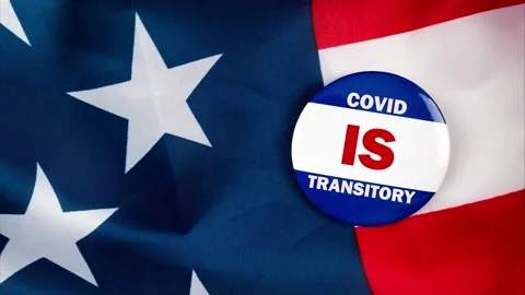 Covid is transitory text quote on election button laying on the star spangled Stock Footage 170629464