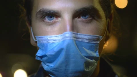 Covid19 - serious man pulls down the mask staring at camera - outdoor at night Stock Footage 142897420