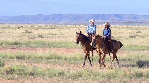 Cowboy and cowgirl on horseback casually walking on a ranch in Texas, Stock Footage