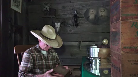 Cowboy in the bunkhouse, man opens old cigar box Stock Footage 61014343