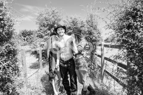 Cowboy, cowgirl couple Male is showing his six pack abs. Both are laughing as Stock Photos