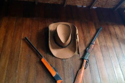Cowboy hat and air rifle on a wooden wall Stock Photos