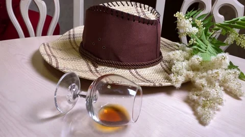 Cowboy hat and wine glass with whiskey on white table Stock Footage 156228564