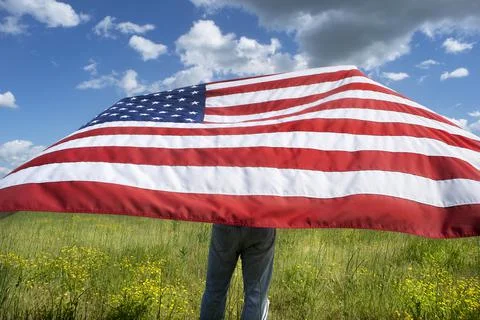 Cowboy holding American flag up blowing in the wind Stock Photos