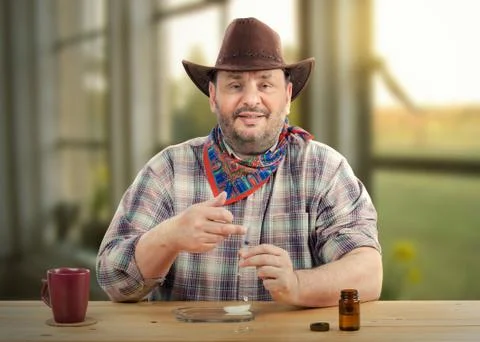 Cowboy knocks air bubbles out of syringe before injection Stockfoto's