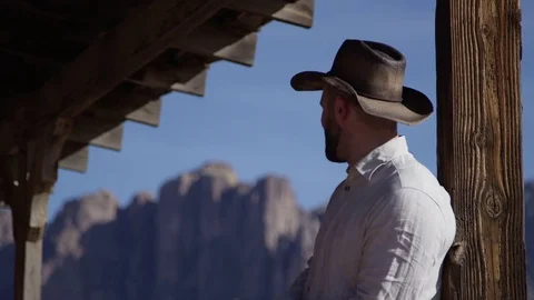 Cowboy man spits in slow motion in front of mountain range in the desert Stock Footage 85292149