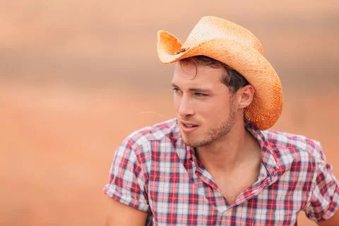 Cowboy man wearing western hat with straw in mouth in country farm background Stock Photos