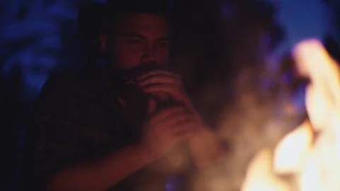 Cowboy plays the harmonica by a campfire at night in slow motion Stock-Footage 128779400