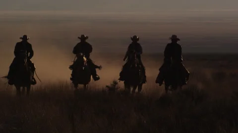 Cowboys riding horses at sunset, slow motion Stock Footage