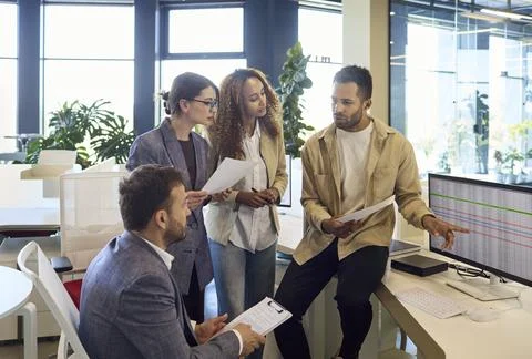 Coworkers analyzing spreadsheet data during strategy meeting at modern Stock Photos