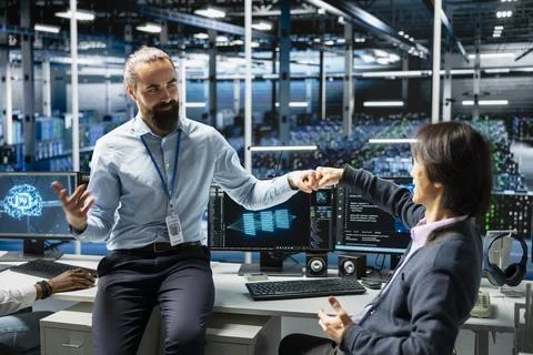 Coworkers coding in data center doing fist bump, pleased after updating AI Foto stock