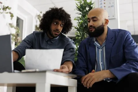 Coworkers collaborating on project while analyzing company documents 库存照片