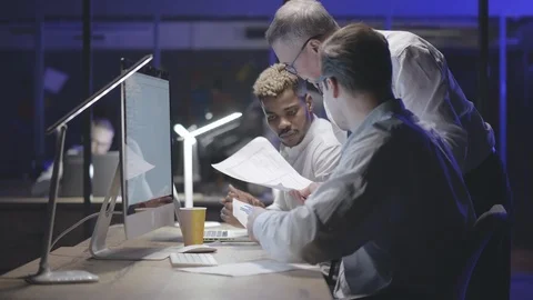 Coworkers with computer and documents working late at night office Stock Footage 125686686