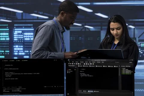 Coworkers in data center doing routine disk checks using laptop and tablet 写真素材