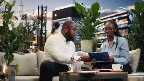 Coworkers discuss project paperwork during rooftop business meeting Stock Footage 345165714