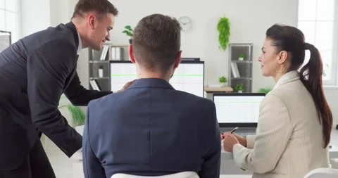 Coworkers discussing data on computer monitors during collaborative office Stock Footage 329286952