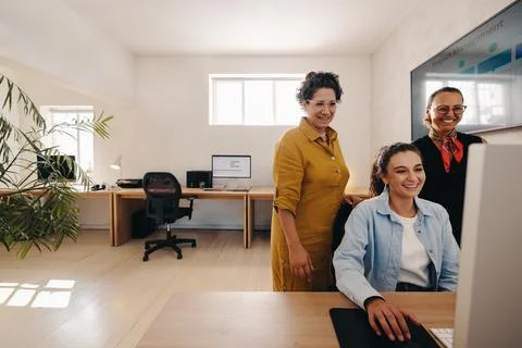 Coworkers looking at project scope on computer in a modern office setting Stock Photos