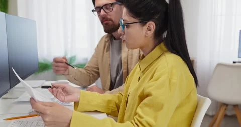 Coworkers reviewing financial documents at computer in modern office teamwork Stockbeeldmateriaal 338271000