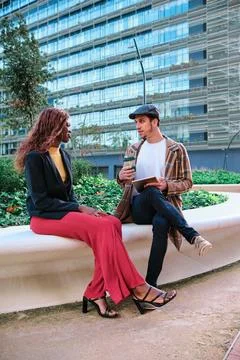 Coworkers talking about work while sitting outdoors in the financial district. Stock Photos