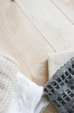 Cozy and soft winter background. Warm knitted clothes on a wooden background. Stock Photos