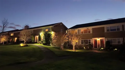 A Cozy Apartment Complex at Dusk Featuring a Beautifully Illuminated Pathway for Vidéo 295074551