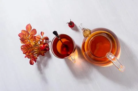 Cozy autumn atmosphere with herbal rose hipe tea in transparent teapot with c Stock Photos