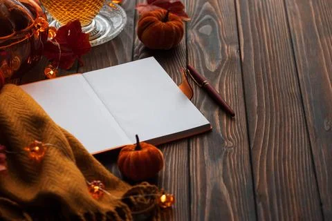 Cozy autumn scene with open notebook, warm drink, pumpkins, and fairy light.. Stock Photos