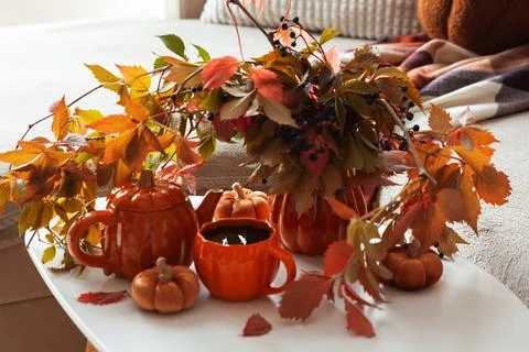 Cozy Autumn Table Setting with Warm Orange Hues and Falling Leaves Stock Photos