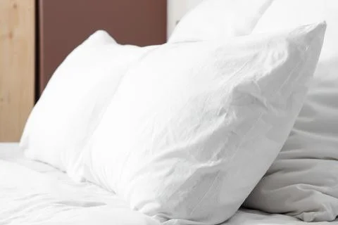 Cozy bed with soft pillows and white bed sheets in stylish bedroom, closeup Stock Photos